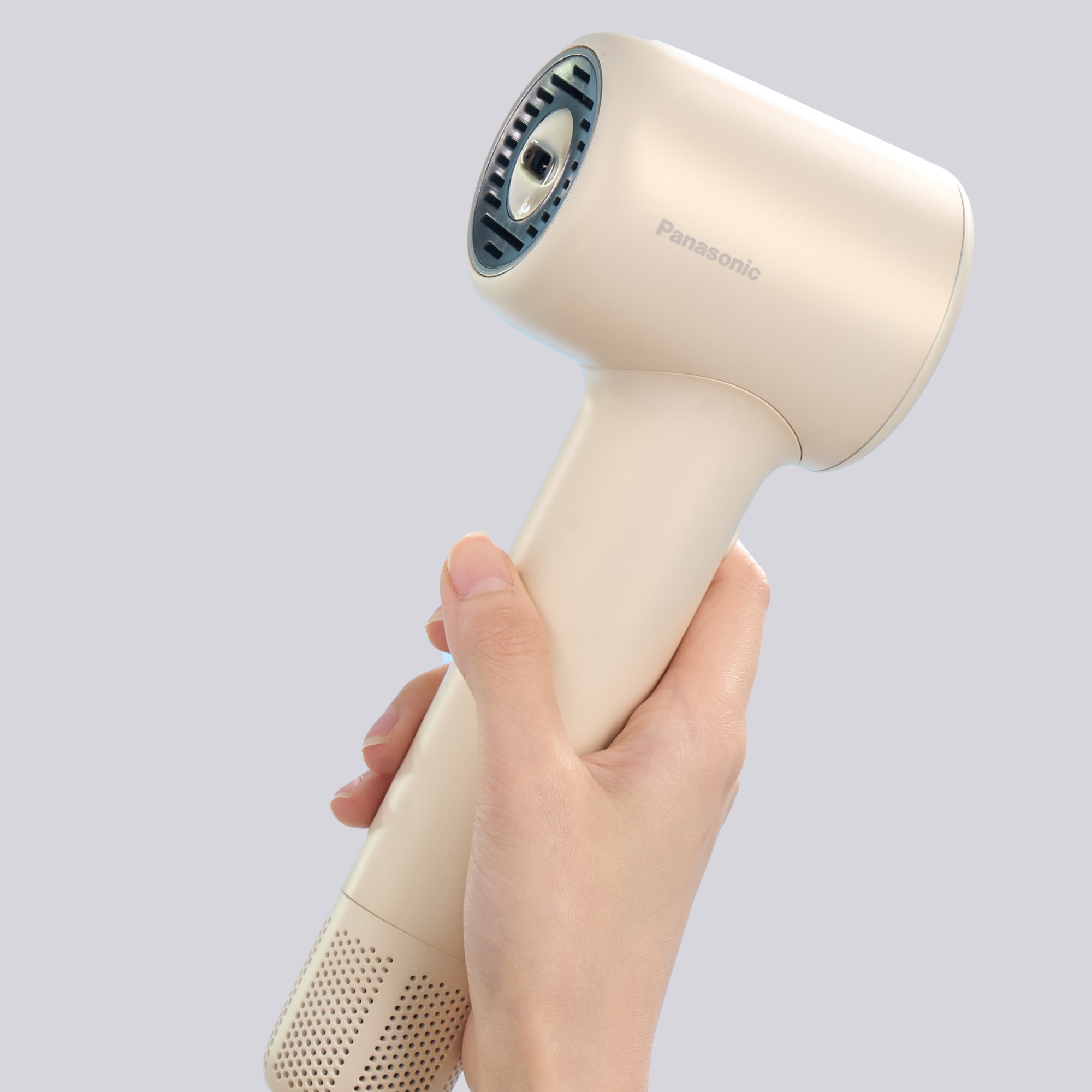 A hand effortlessly holding the compact, cream-colored Panasonic hair dryer, emphasizing the product's lightweight design and ease of handling.